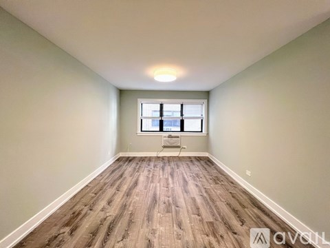 A room with wooden flooring and a window with blinds.