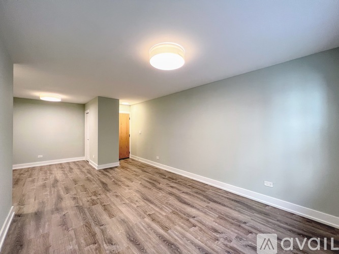 A room with a wooden floor and a door in the background.
