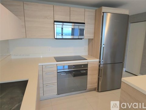 A modern kitchen with a stainless steel refrigerator and oven.