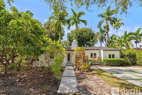 A white house with a garden in front of it.