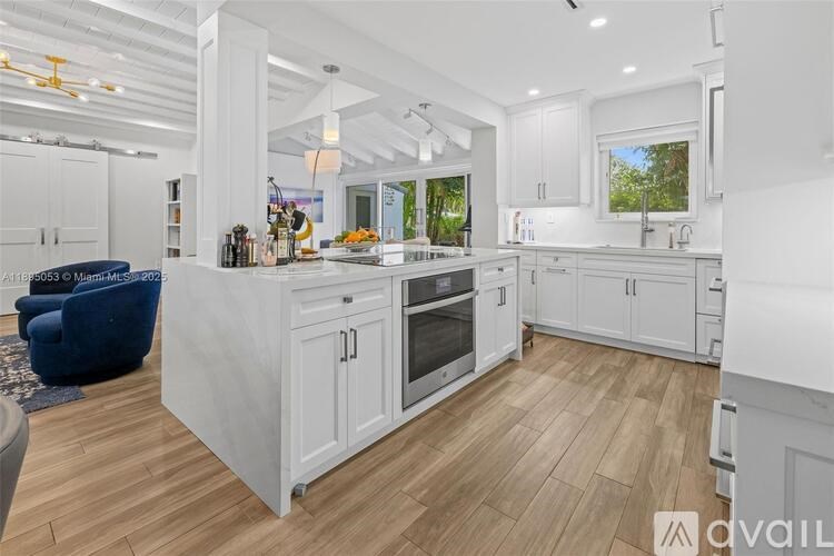 A modern kitchen with white cabinets and a wooden floor.