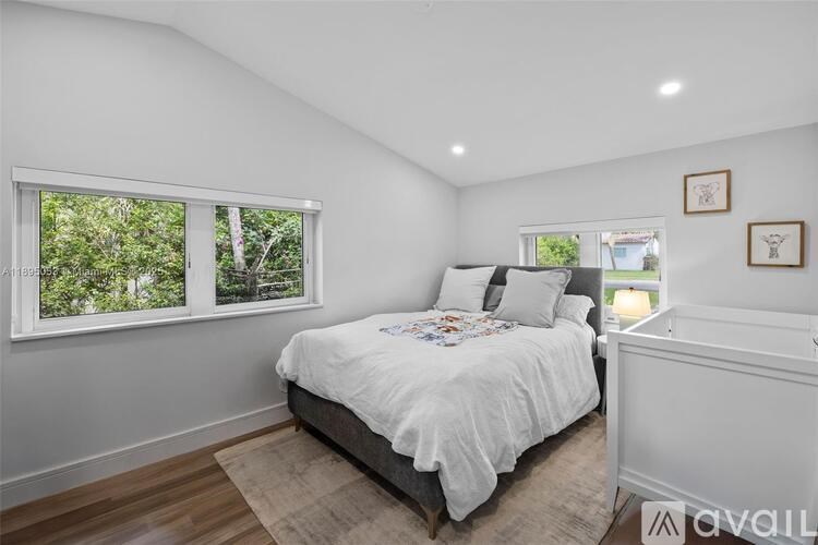 A bedroom with a large bed and a window overlooking a green area.