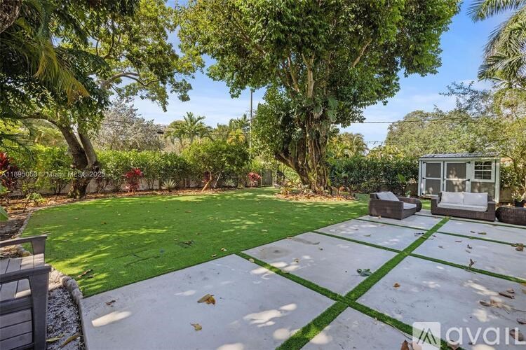 A backyard with a green lawn and a white shed.