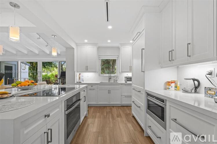 A modern kitchen with white cabinets and a wooden floor.