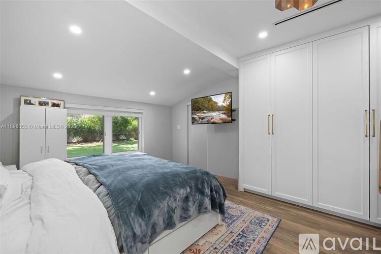 A bedroom with a large bed and a television mounted on the wall.