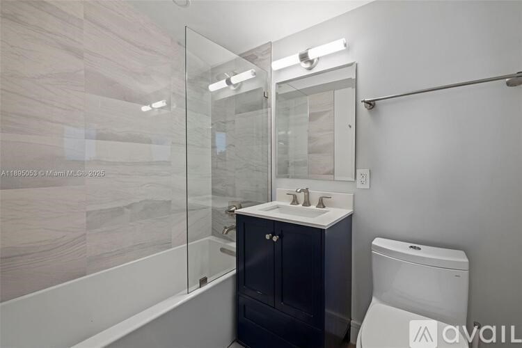 A bathroom with a white toilet, a sink with a cabinet and a glass shower stall.