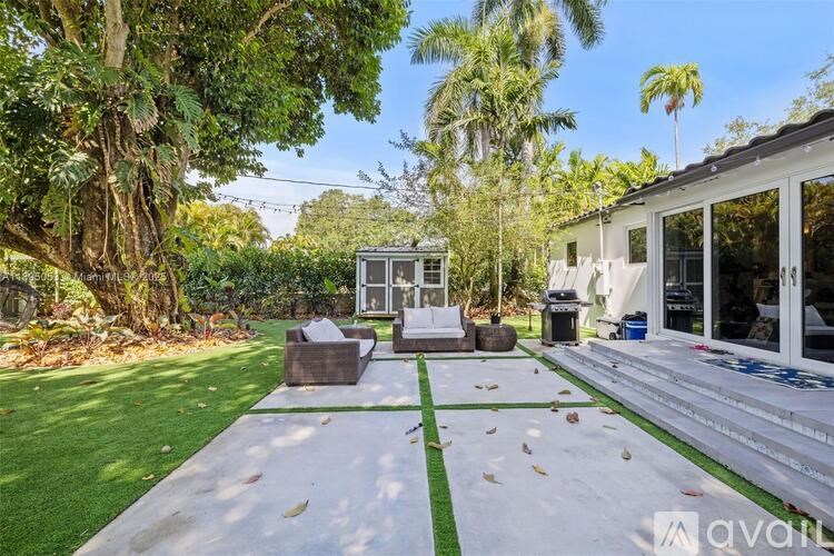 A backyard with a lawn, a white couch, and a small house.