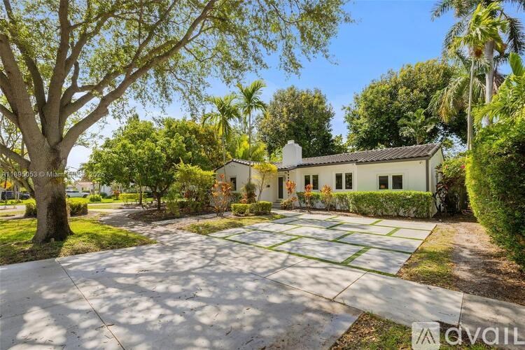 A house with a driveway and trees in front of it.
