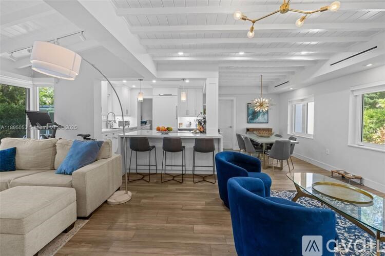 A modern living room with a dining area and a kitchen in the background.