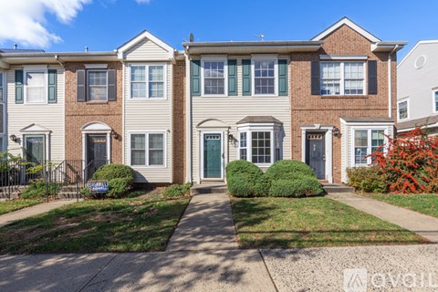 A row of townhouses with a blue sign in front of the first one.