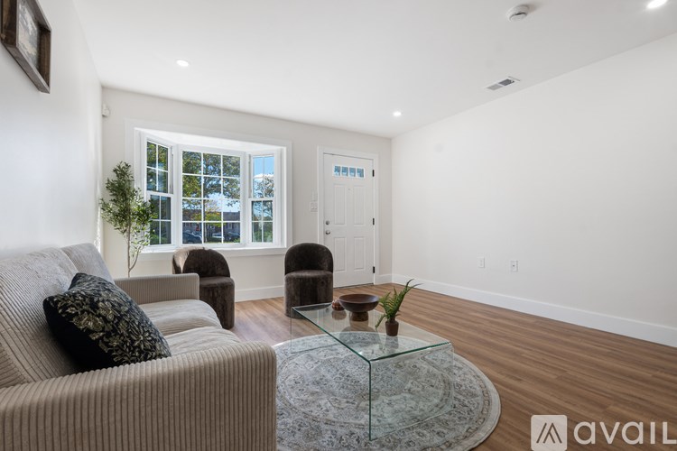 A living room with a couch, chairs, and a glass coffee table.