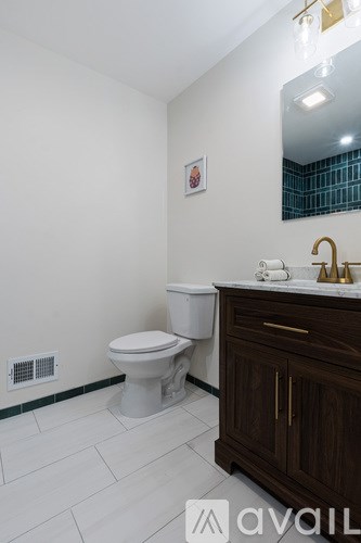 A bathroom with a toilet, sink, and mirror.