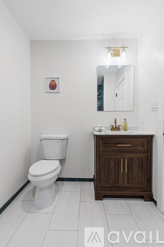 A white toilet sits next to a wooden cabinet in a bathroom.