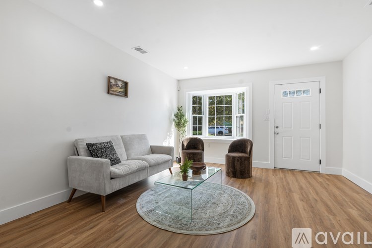 A living room with a grey couch, a glass coffee table, and a painting on the wall.