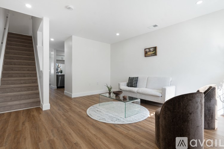 A living room with a white couch, a glass coffee table, and a brown armchair.