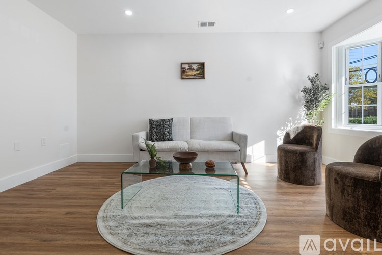 A living room with a glass coffee table and a white couch.
