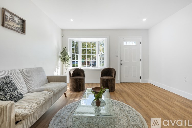 A living room with a couch, two chairs, and a glass coffee table.
