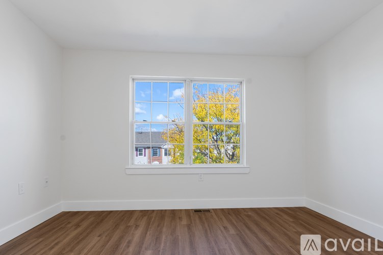 A room with a window showing a view of a house and trees.