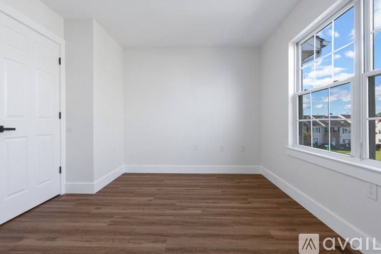 A room with a wooden floor and a window showing a view of the outside.
