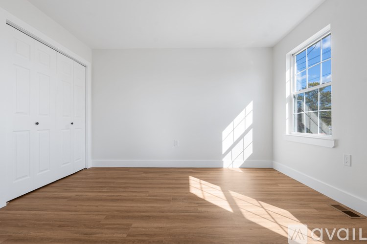 A room with wooden floors and a large window letting in sunlight.