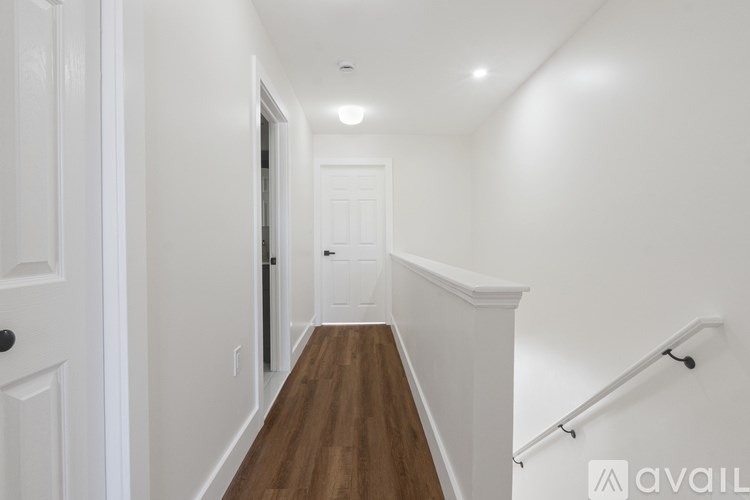 A hallway with a wooden floor and white walls.