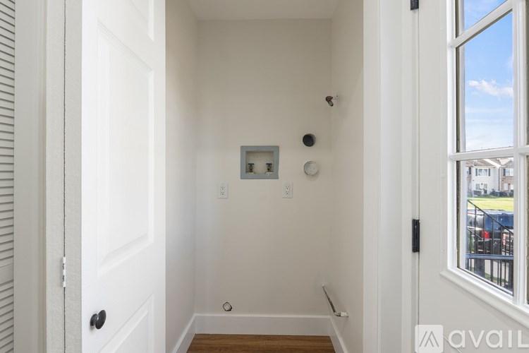 A white door with a black handle is open to a hallway.