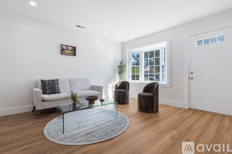 A living room with a white couch, a glass coffee table, and a rug.