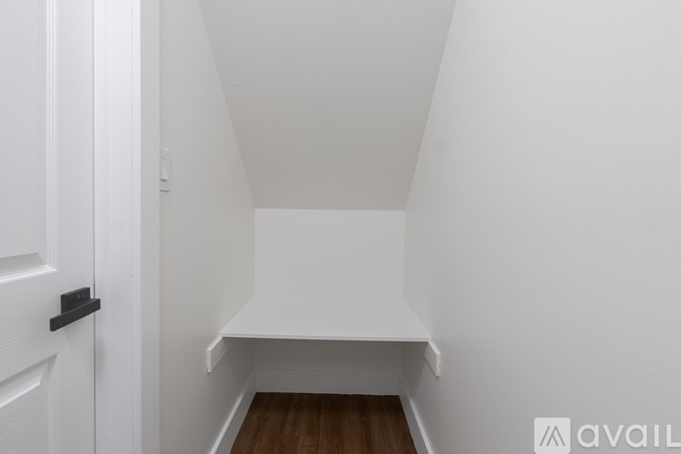A white room with a wooden floor and a white door.
