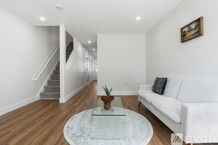 A living room with a white couch and a glass coffee table.