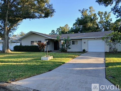 A house with a driveway and a tree in front of it.