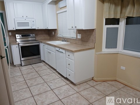 A kitchen with white cabinets and a tiled floor.