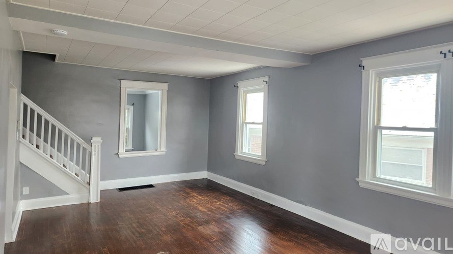 A room with a staircase and two windows.