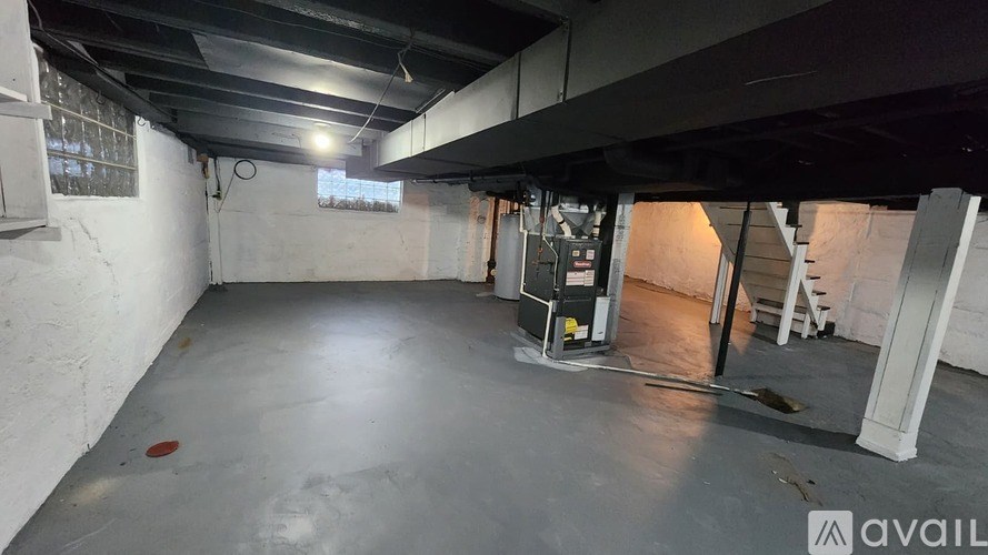 A large, empty basement with concrete floors and walls, and a metal staircase leading to another level.