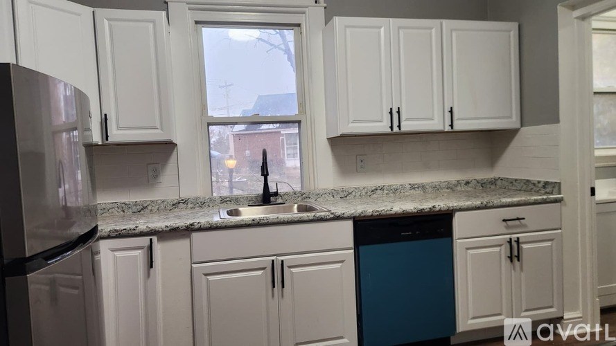 A kitchen with white cabinets and a blue dishwasher.