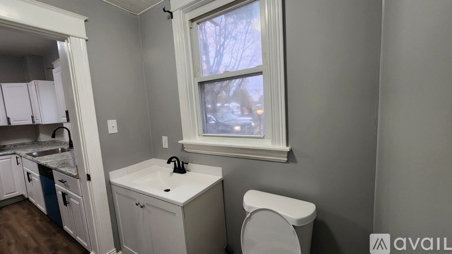 A small bathroom with a toilet, sink, and a window.