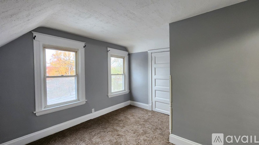 A room with grey walls and a window showing autumn trees outside.