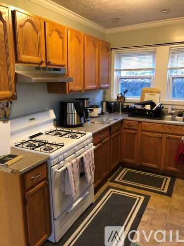 A kitchen with a white stove top oven and wooden cabinets.