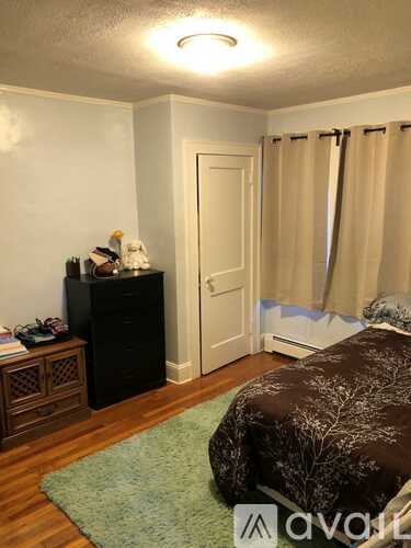 A bedroom with a bed, dresser, and window with curtains.