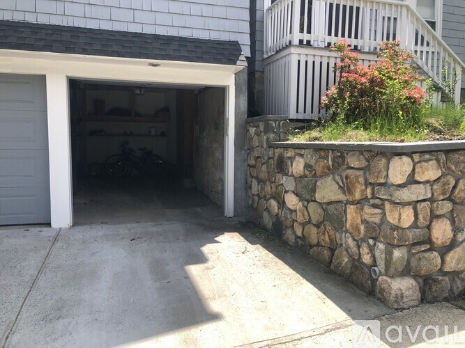 A garage with a stone wall and a staircase outside.