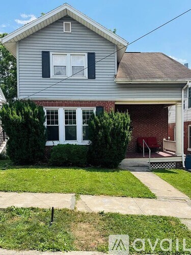 A house with a grey siding and a red brick wall.