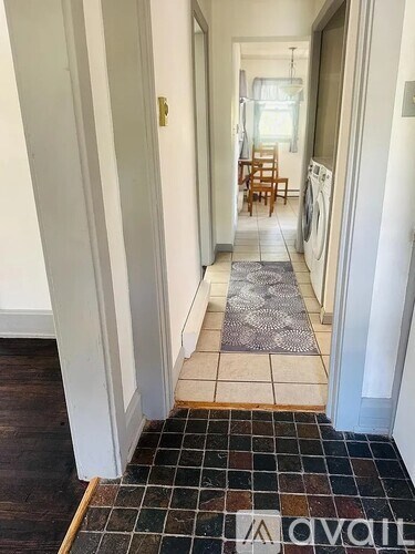 A hallway with a tiled floor and a rug in the middle.