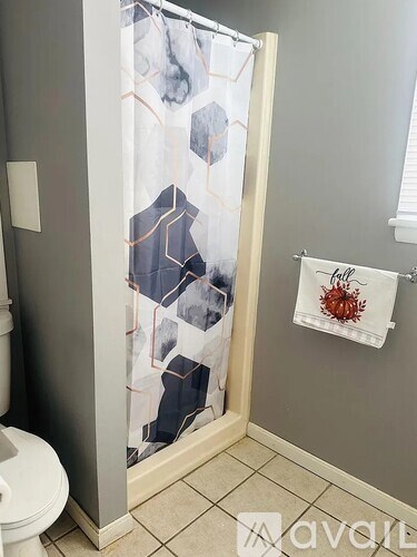 A bathroom with a shower curtain and a towel hanging on the wall.