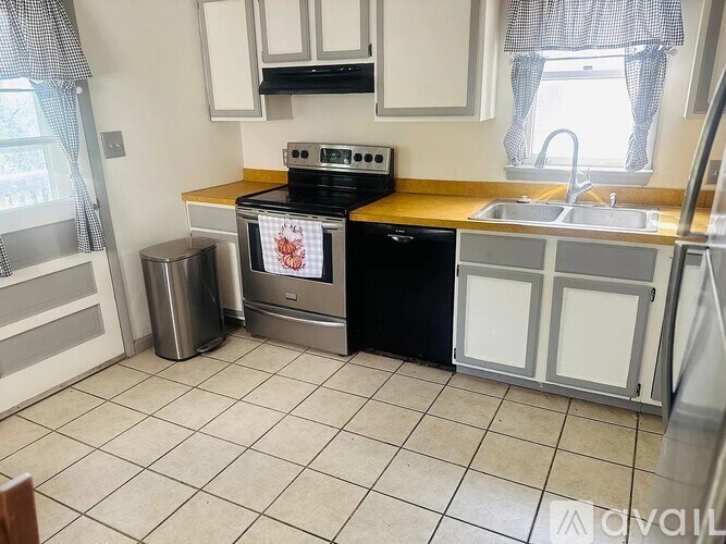 A kitchen with a black dishwasher and a stove top oven.