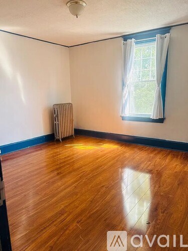 A room with wooden floors and a window with curtains.