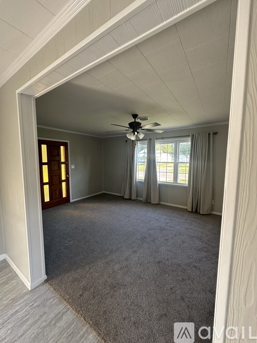 A room with a ceiling fan and a window with curtains.