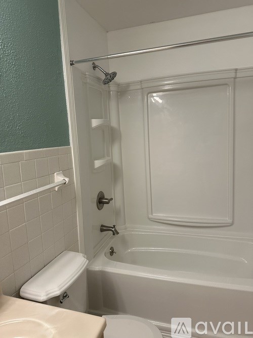 A white toilet sits next to a white bathtub in a bathroom.