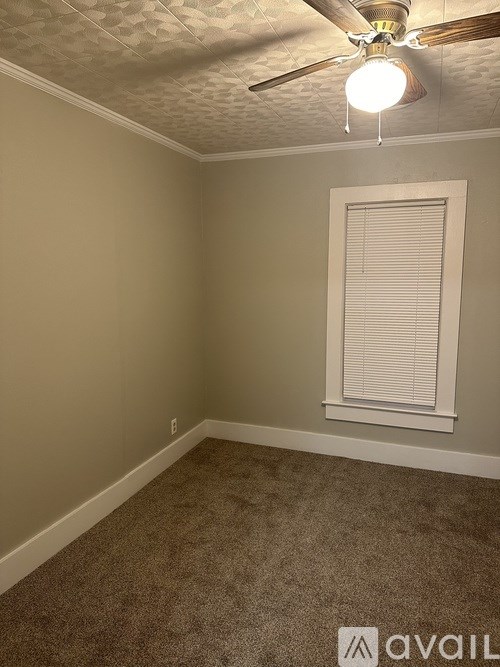 A room with a ceiling fan and a window with blinds.