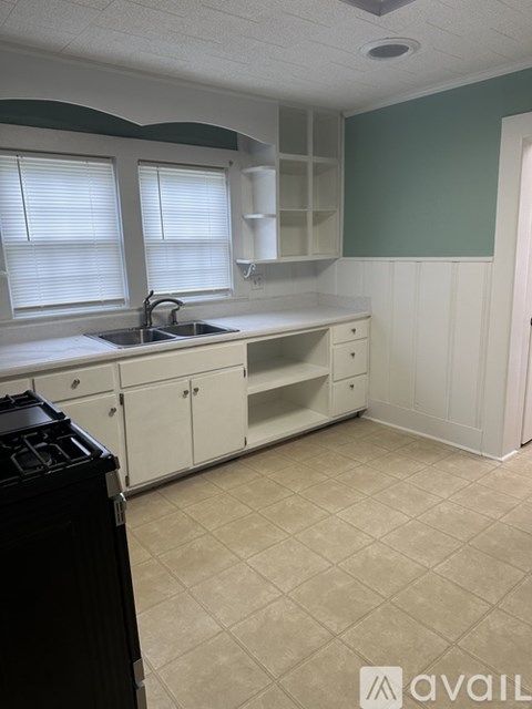 A kitchen with white cabinets and a black stove top oven.