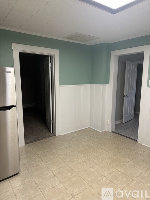 A kitchen with a refrigerator and two doors open.