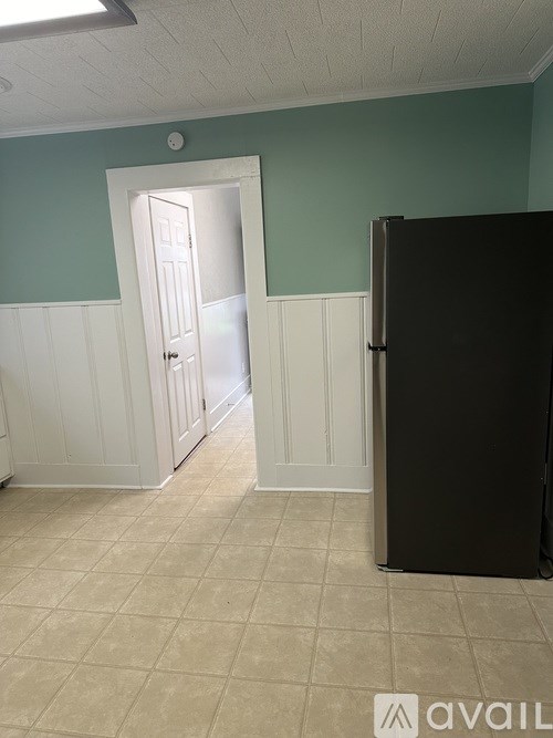 A room with a black refrigerator and a white door.